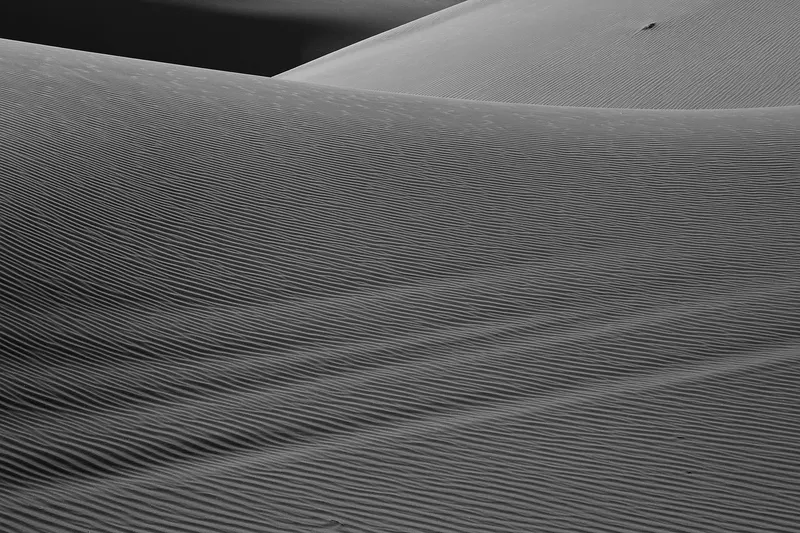 A minimalist desert landscape with clean lines and soft sunlight reflecting off sand